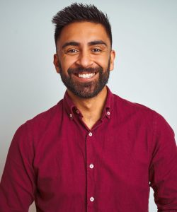 Young indian man wearing red elegant shirt standing over isolated grey background with hands together and crossed fingers smiling relaxed and cheerful. Success and optimistic