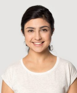 Headshot portrait of happy indian millennial girl stand isolated on grey studio background wear t-shirt look at camera, smiling ethnic young woman posing showing white healthy teeth, dental treatment